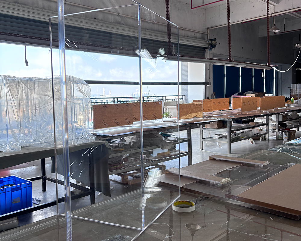 Tall vertical clear acrylic partition wall semi-finished panel leaning against factory workbench with city window view