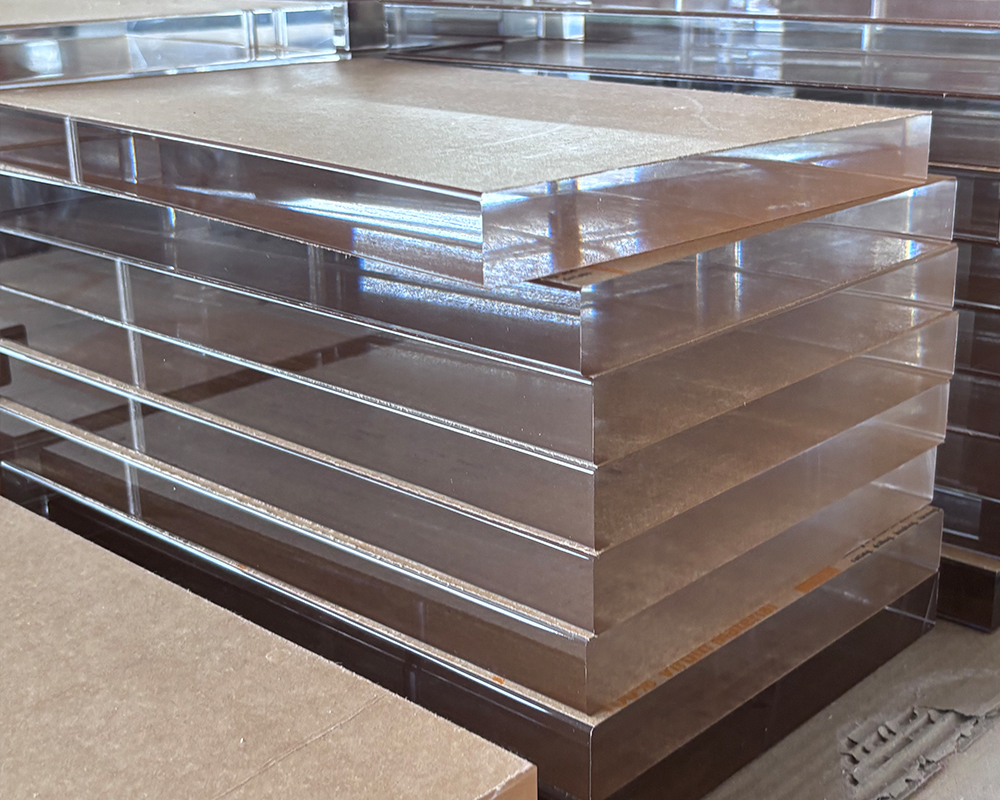 Multiple layers of thick transparent solid acrylic sheet stock neatly stacked inside factory