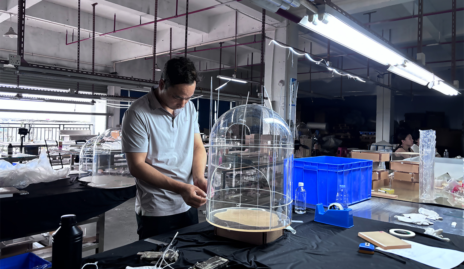 Factory worker assembling large clear bubble acrylic cat villa enclosure in acrylic production workshop