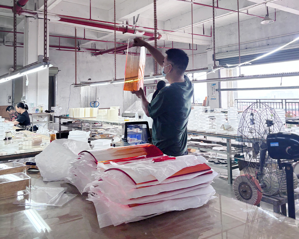 Factory staff handling gradient orange translucent acrylic furniture panels at assembly station