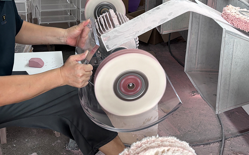 Worker polishing acrylic edge with rotary buff wheel machine, acrylic processing workshop