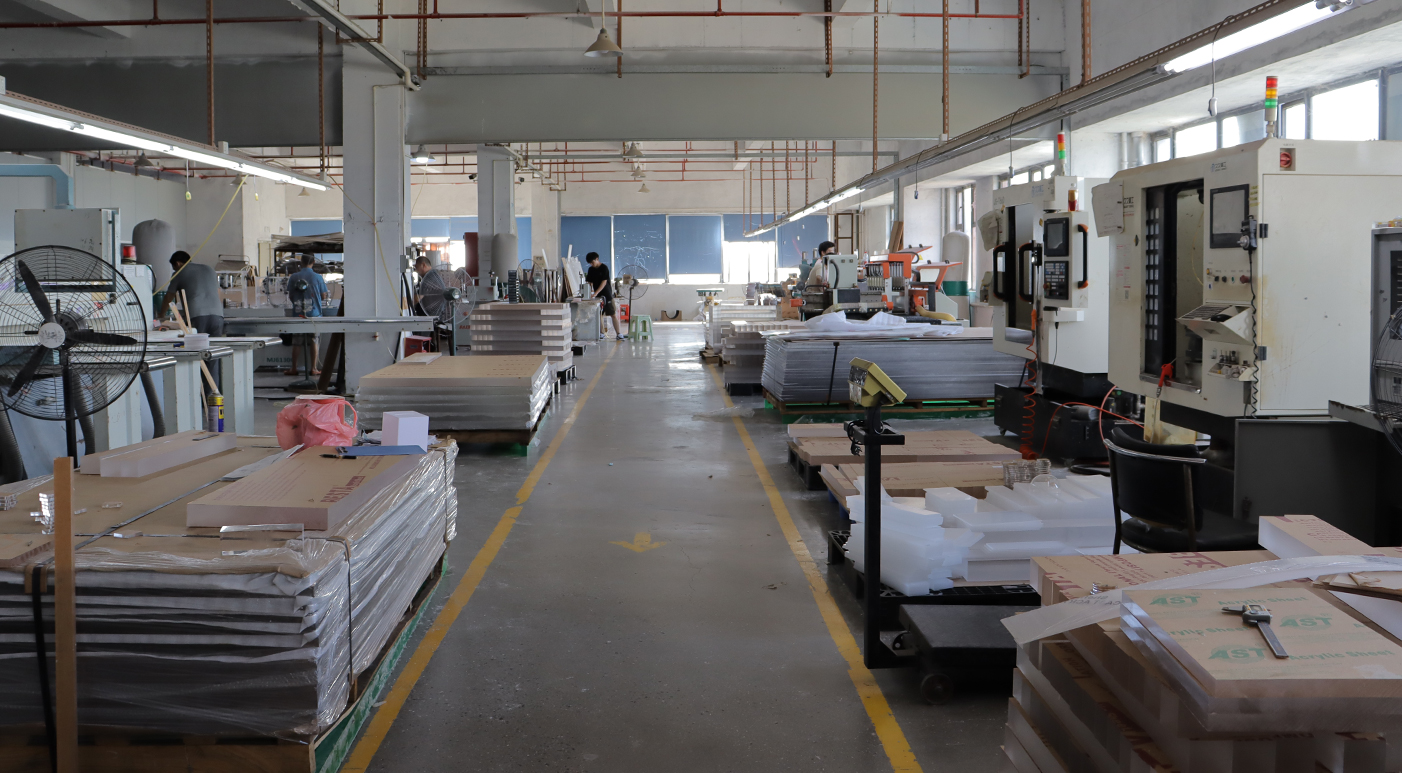 Wide empty factory aisle with stacked acrylic raw material boards and production equipment