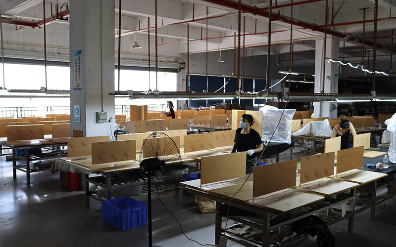 Acrylic custom factory workshop, workers assembling flat acrylic panels at workstations