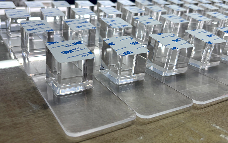 Precision acrylic display assembly with 3M 9448A adhesive tape, high-clarity lucite blocks with industrial-grade bonding for tech retail fixtures.