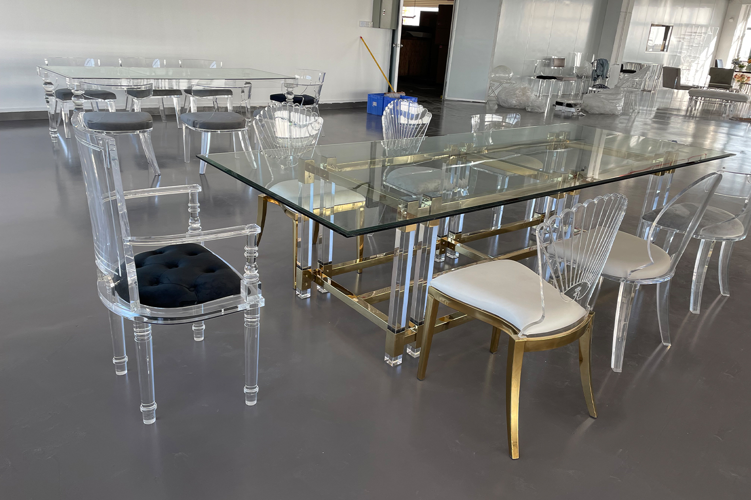 Clear Acrylic Dining Chairs and Rectangular Table with Gold Metal Base in a Showroom