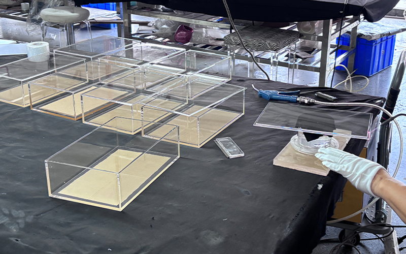 Manual Assembly of Clear Acrylic Display Trays on a Factory Workbench