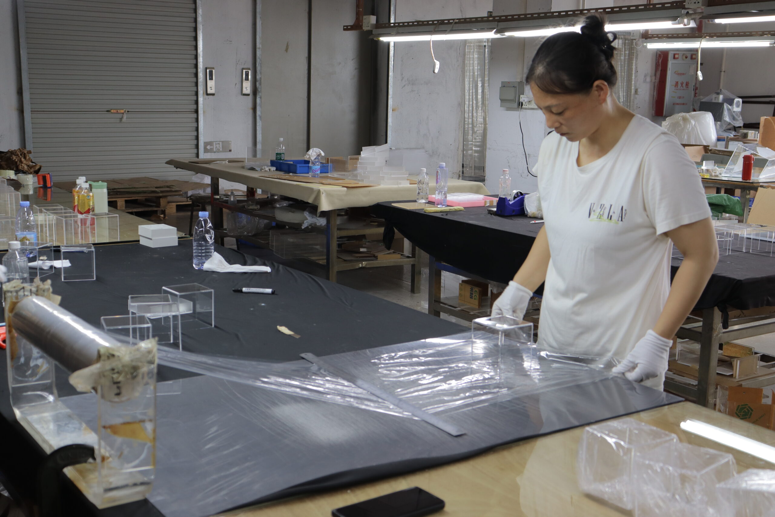 Worker Applying Protective Film to Clear Acrylic Display Boxes before Packaging