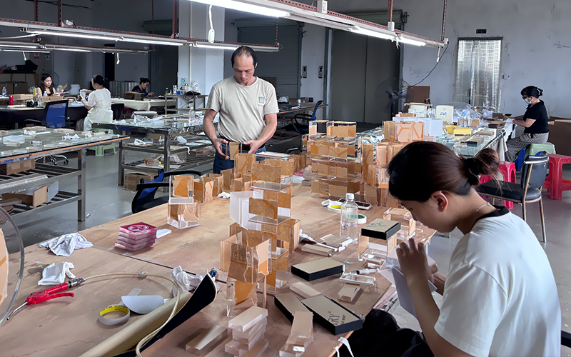 Workers Manually Assembling and Packing Clear Acrylic Display Boxes in a Workshop