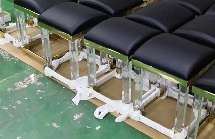 Black upholstered stools with clear acrylic legs and gold trim
