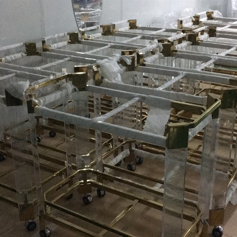 Gold metal and clear acrylic bar carts in factory workshop