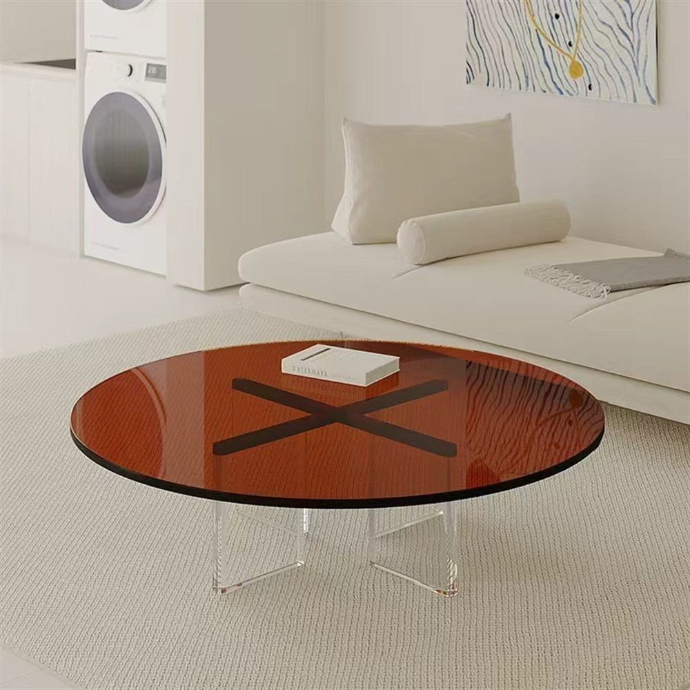Round amber acrylic coffee table with clear cross base in living room