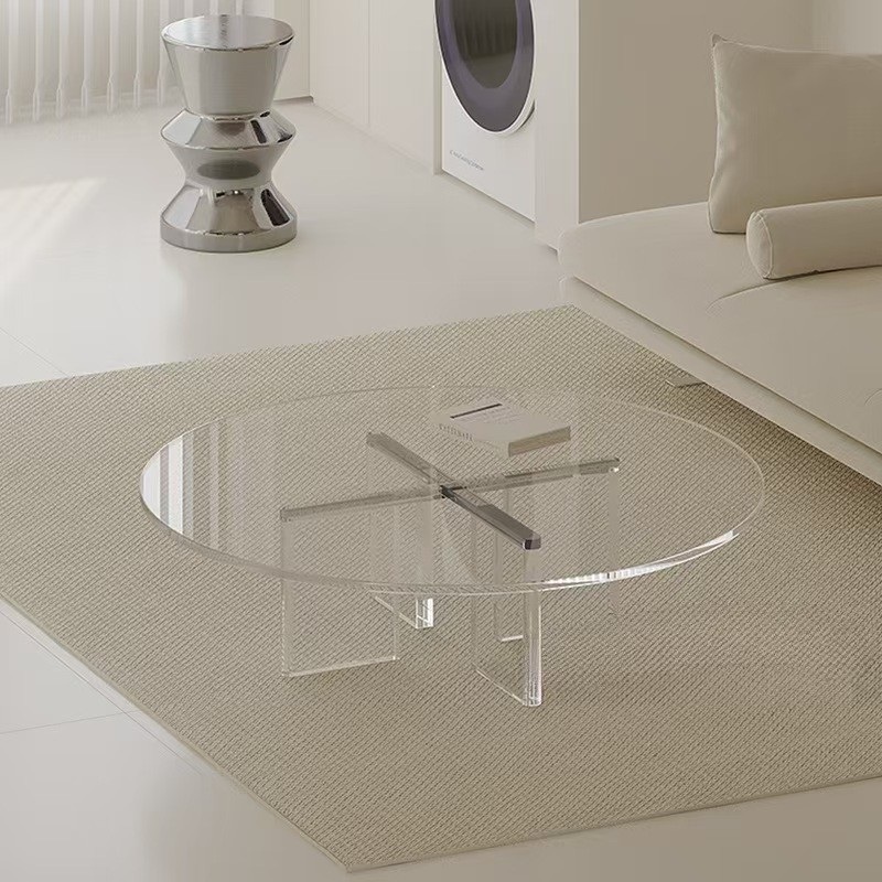 Round clear acrylic coffee table with X shape base in living room