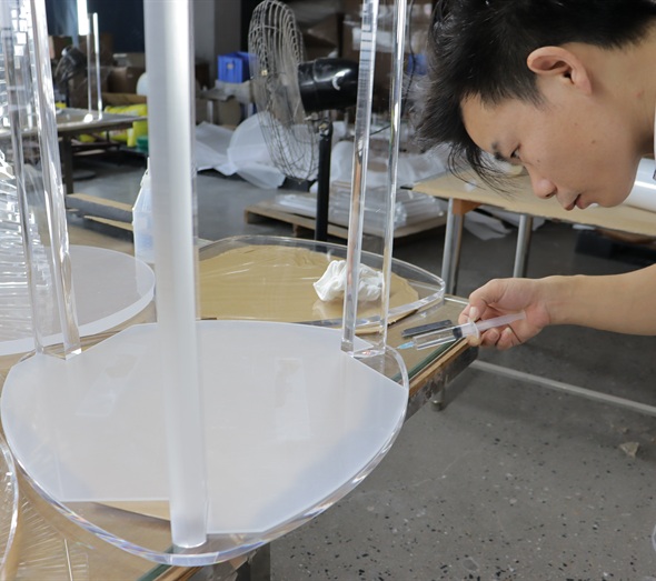 Technician bonding clear acrylic furniture component