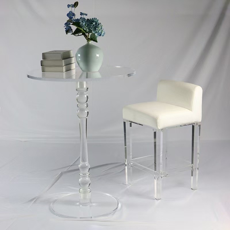 White upholstered acrylic dining chair beside clear pedestal table