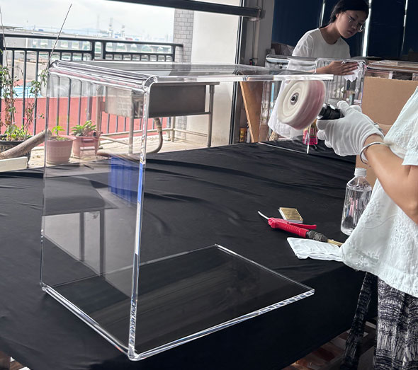 Worker assembling clear acrylic display stand in workshop