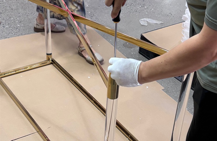 Worker assembling gold metal frame and clear acrylic console table