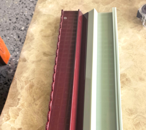 Close-up view of custom acrylic mahjong tile rack extrusions in burgundy red and mint green with grooved tile pusher design.